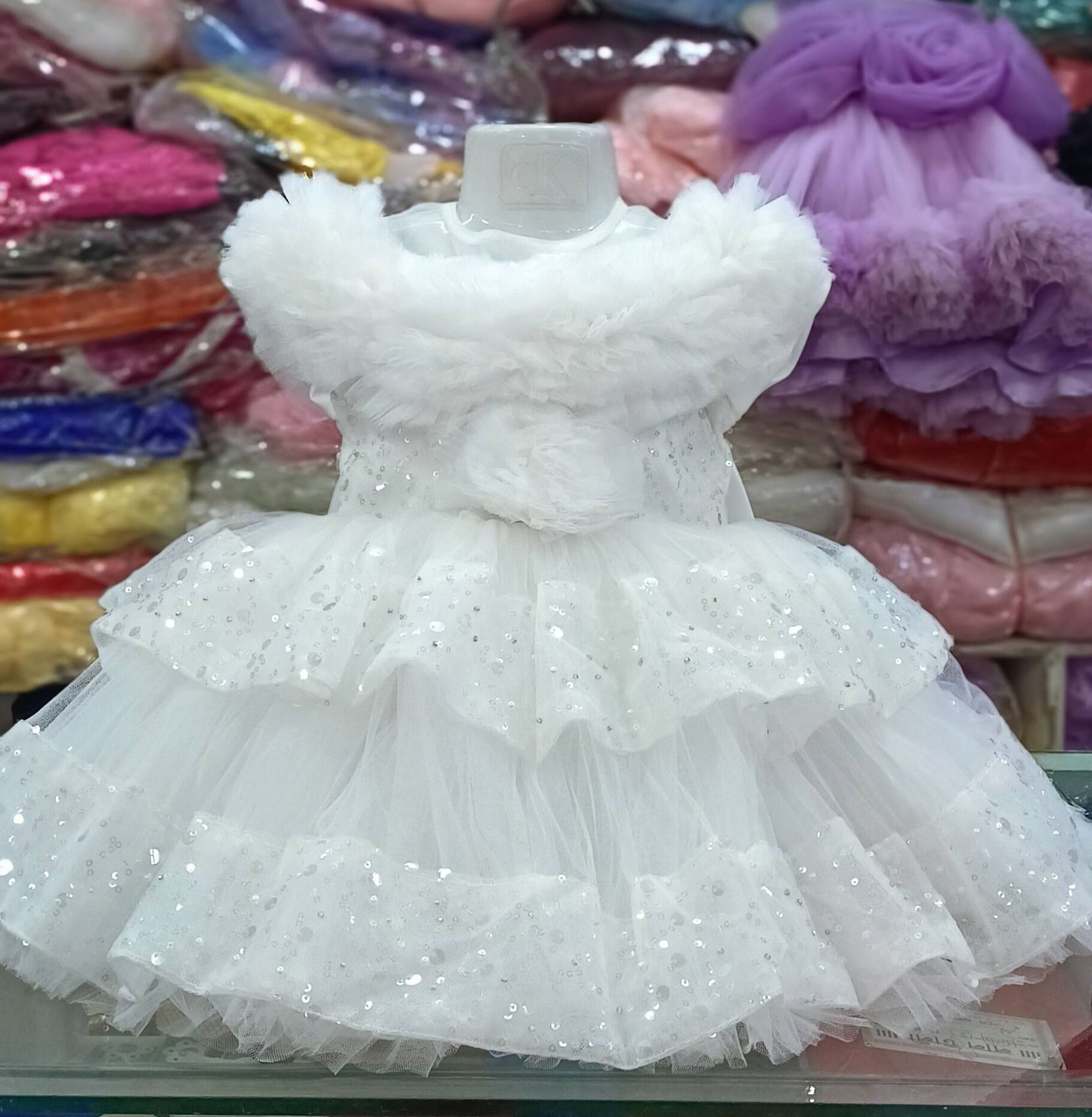 Premium White Shimmery Baby Dress Ball Gown with silver sequined tiered ruffles, off-the-shoulder fluffy net design, and floral waist accent - HKD920 - Kiddleplace