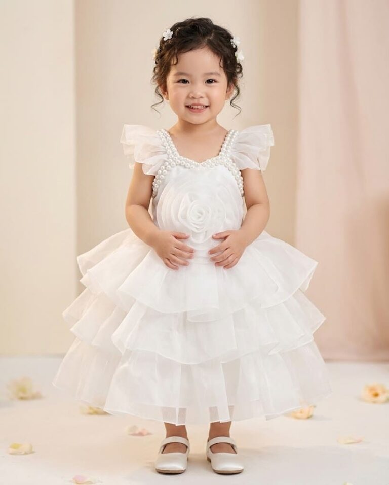 Little girl in a beautiful snow white layered net party dress with large 3D rose and pearl neck design.