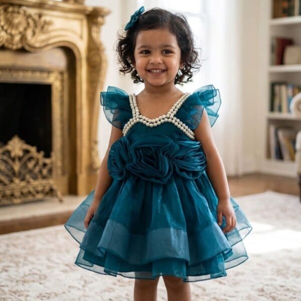 Baby girl in a teal blue luxury net party frock with 3D roses and pearl neckline.