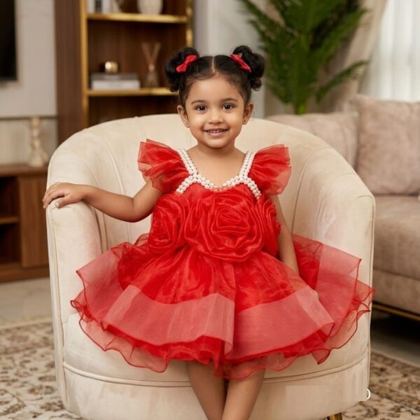 Little girl wearing a premium red party dress featuring large 3D organza roses on the front and a pearl-studded neckline