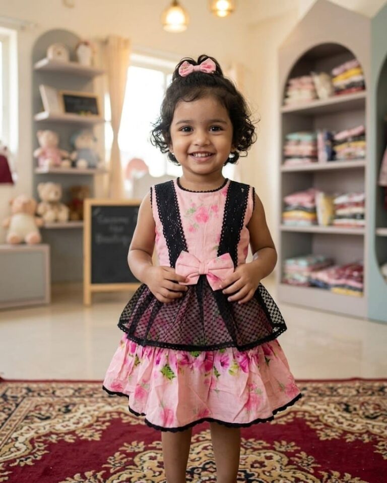 Baby girl in a luxury baby pink net frock with large 3D roses and pearl neckline.