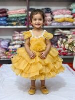 Baby girl wearing a mustard yellow layered net party frock with pearl neckline and 3D rose.