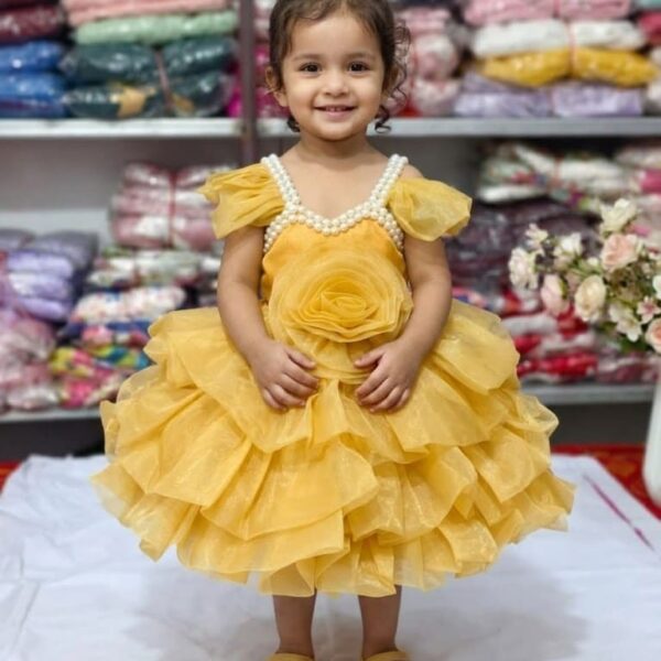 Baby girl wearing a mustard yellow layered net party frock with pearl neckline and 3D rose.