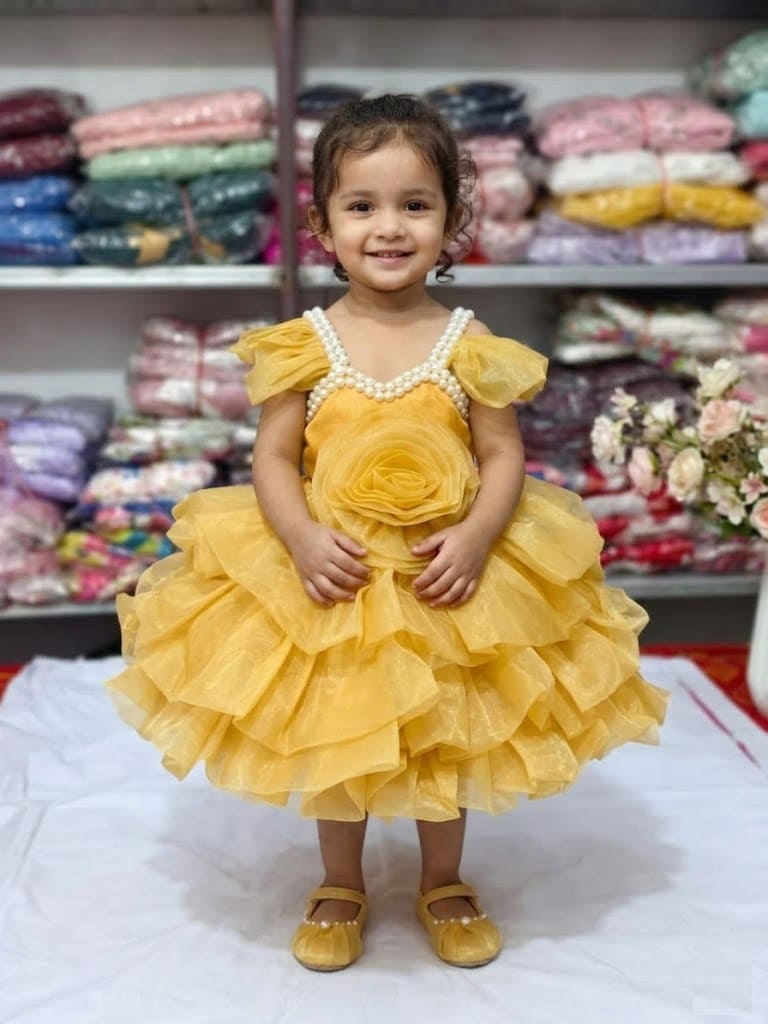 Baby girl wearing a mustard yellow layered net party frock with pearl neckline and 3D rose.
