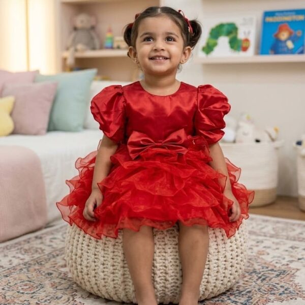 Toddler girl wearing a vibrant red silk-finish puff sleeve dress with a layered ruffle skirt and waist bow
