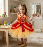 Little girl wearing a yellow tulle party dress with red floral embroidery, red waist bow, and pearl details.